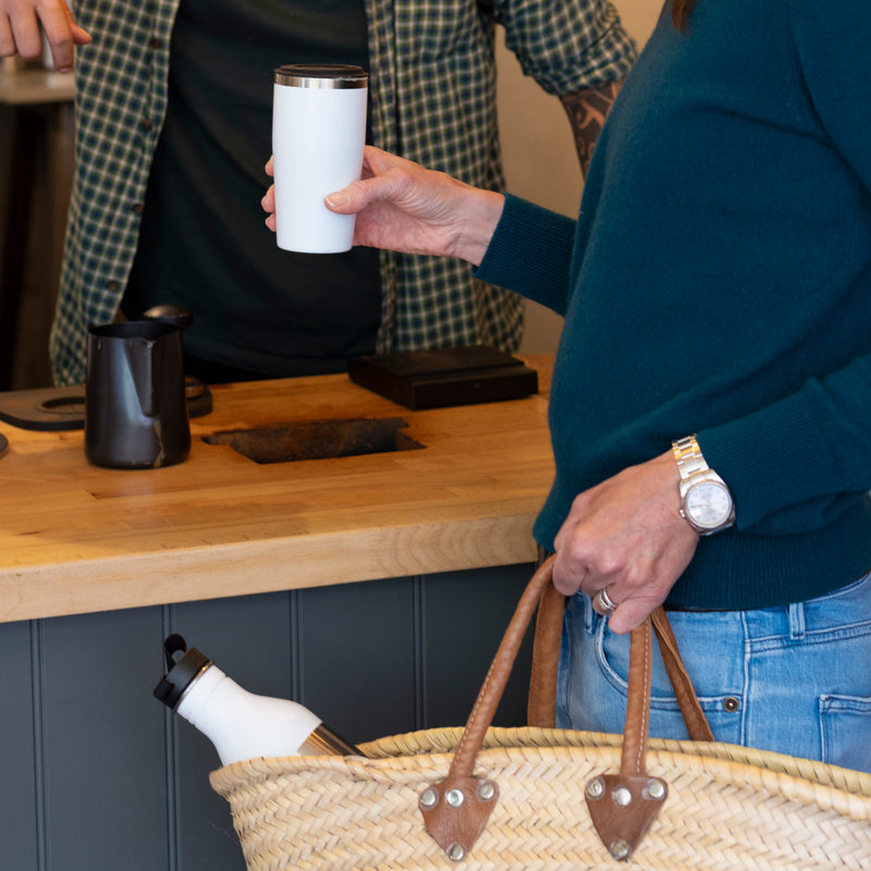 Cupple reusable water bottle and insulated reusable cup white in use at coffee shop