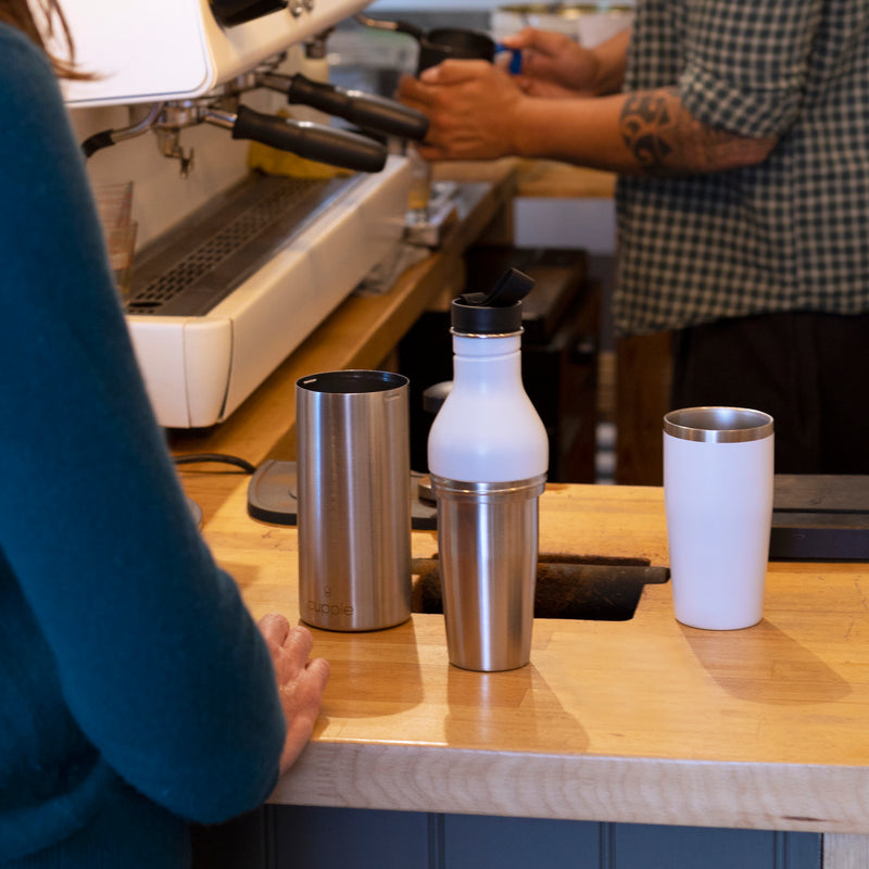 Cupple reusable water bottle and insulated reusable cup white in use at coffee shop